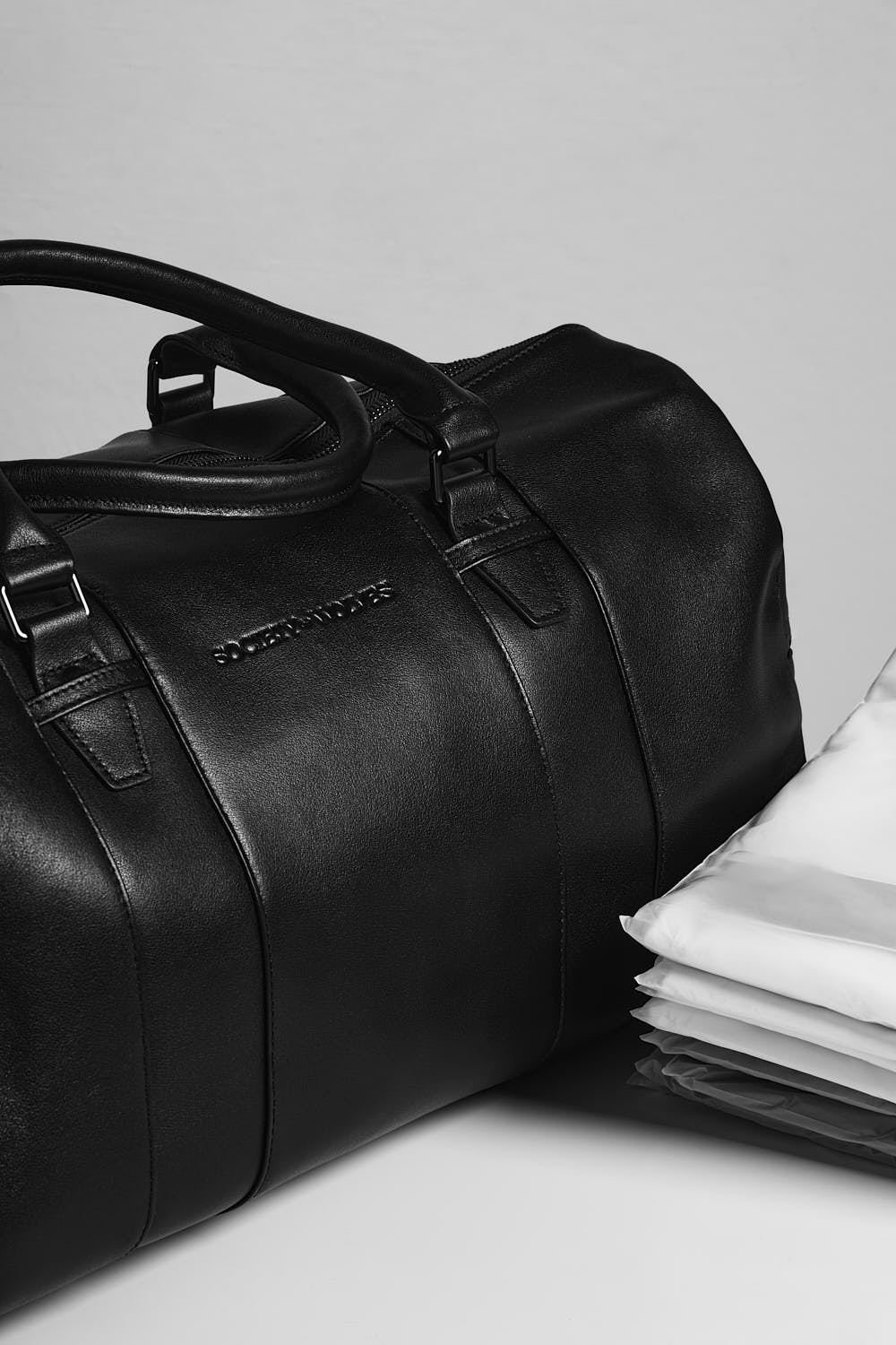 Black leather travel bag with folded shirts.